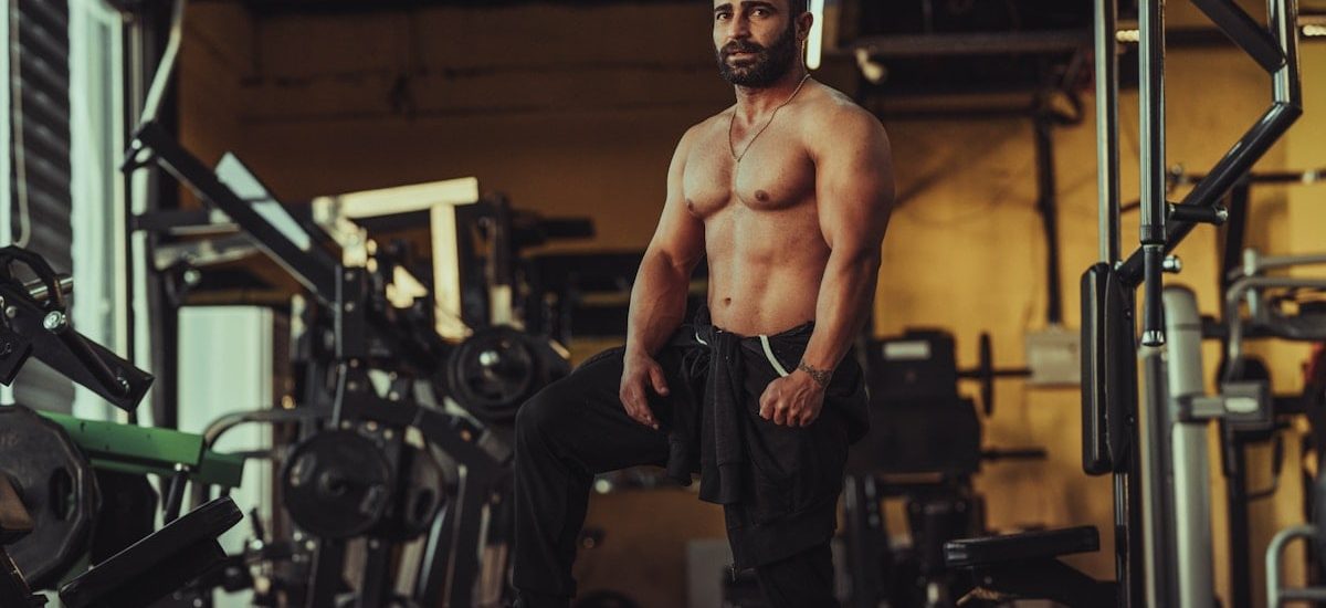 a shirtless man standing in a gym