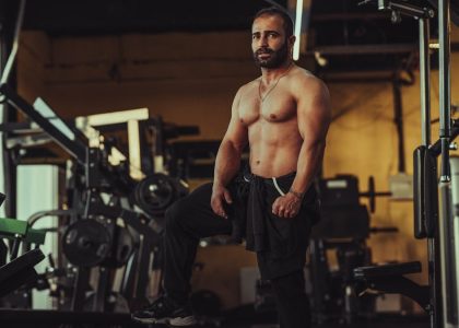 a shirtless man standing in a gym